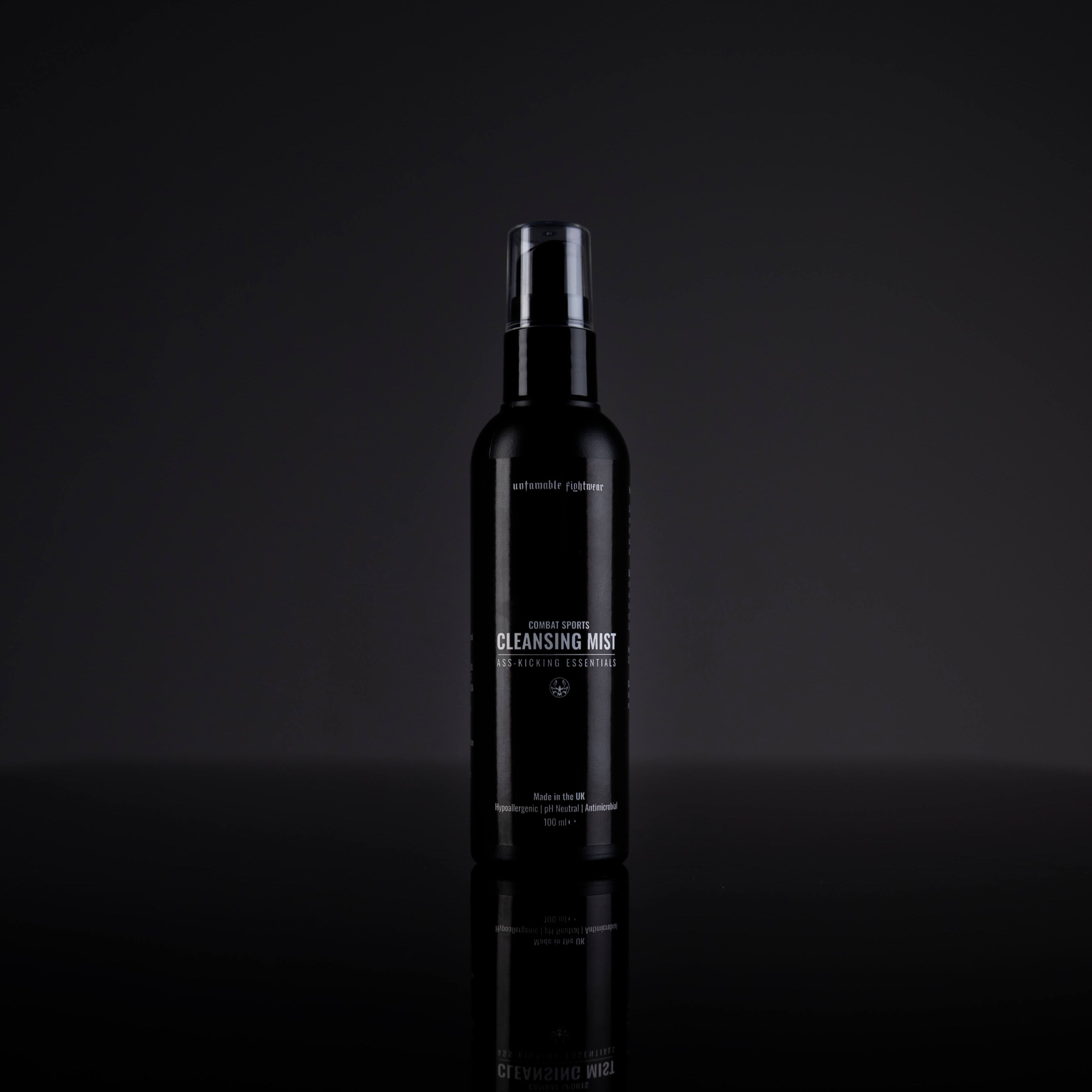Black bottle of cleansing mist on a reflective black surface with a dark background